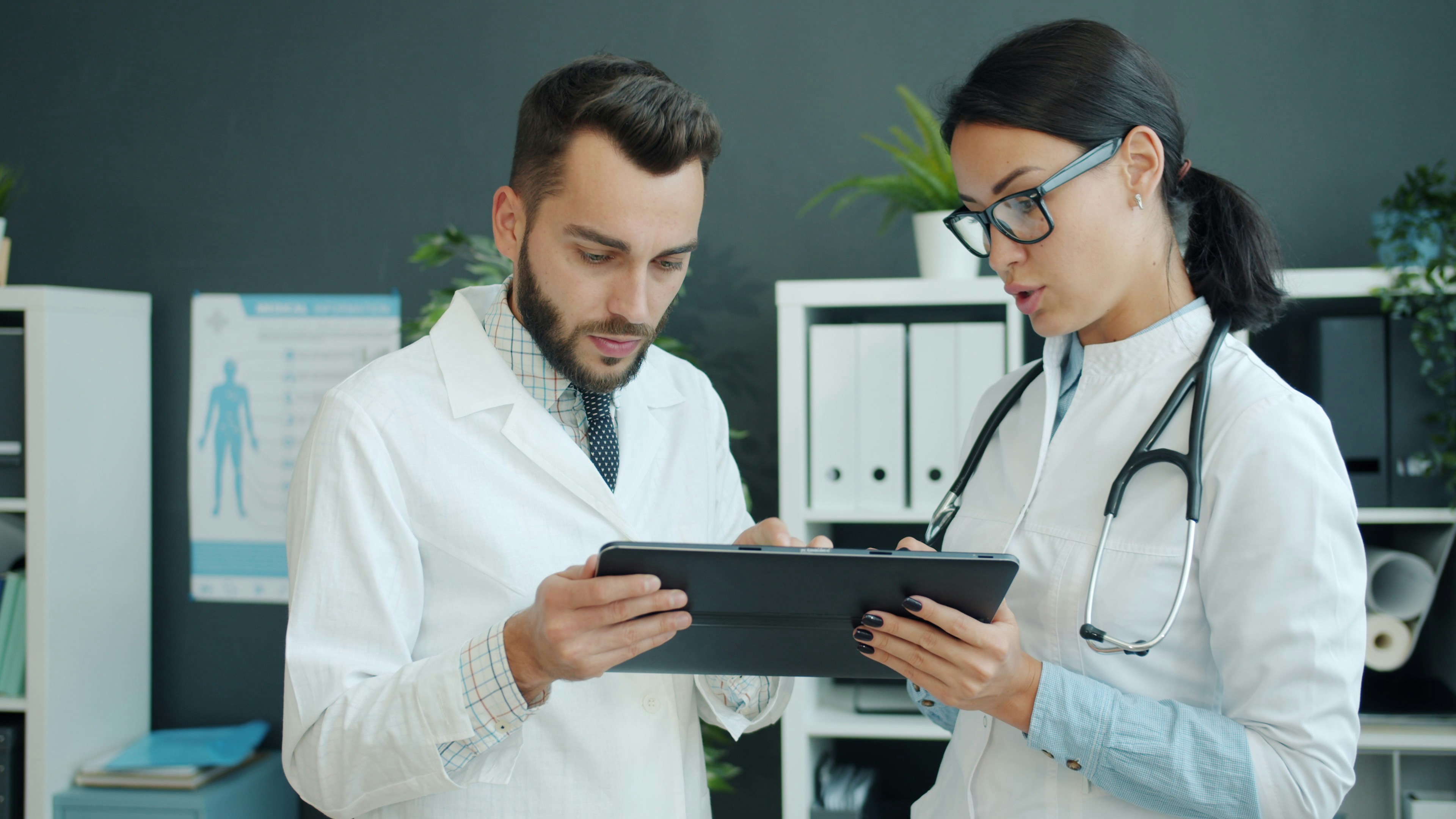 Two healthcare professionals reviewing information on a tablet in an office setting.
